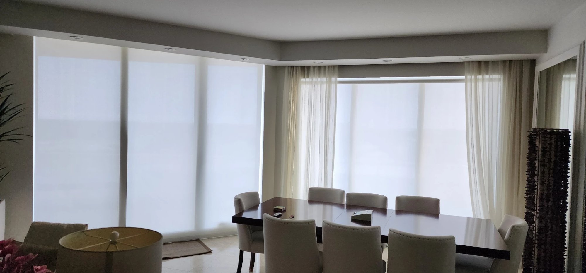 Motorized sheer shades with drapery in a modern dining room with floor-to-ceiling windows
