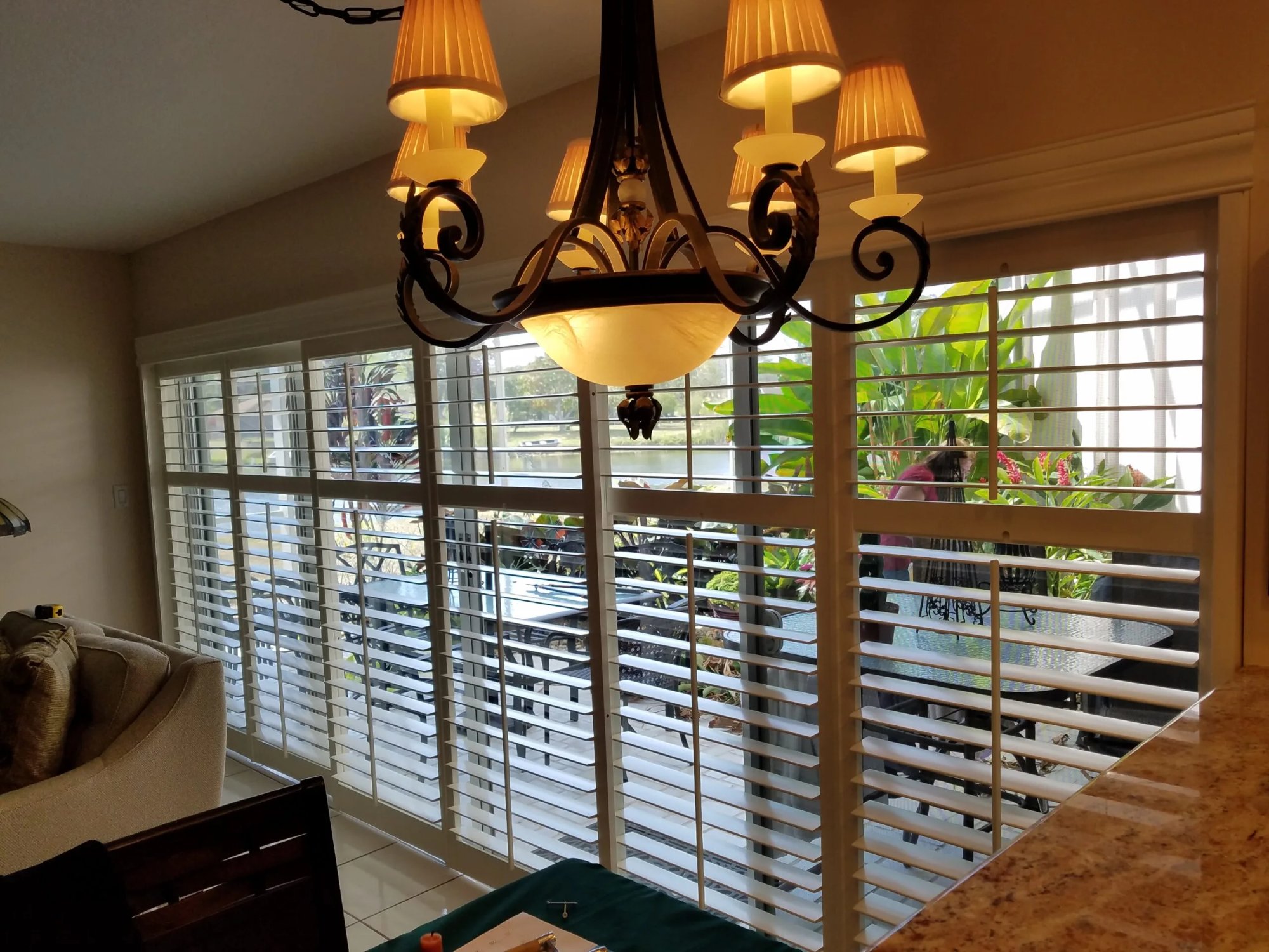 Plantation shutters on large living room windows overlooking tropical landscaping