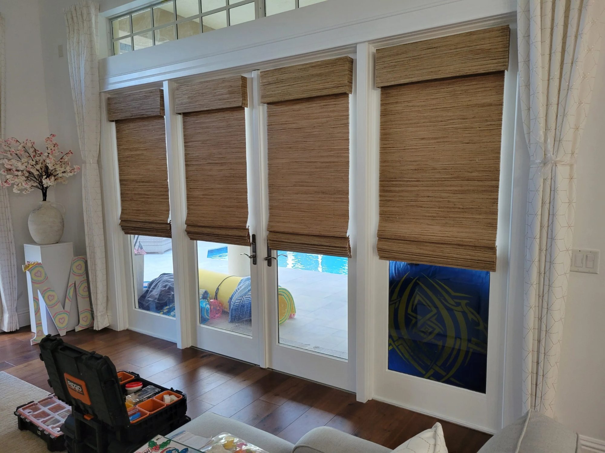 Woven wood shades on French doors leading to a pool area