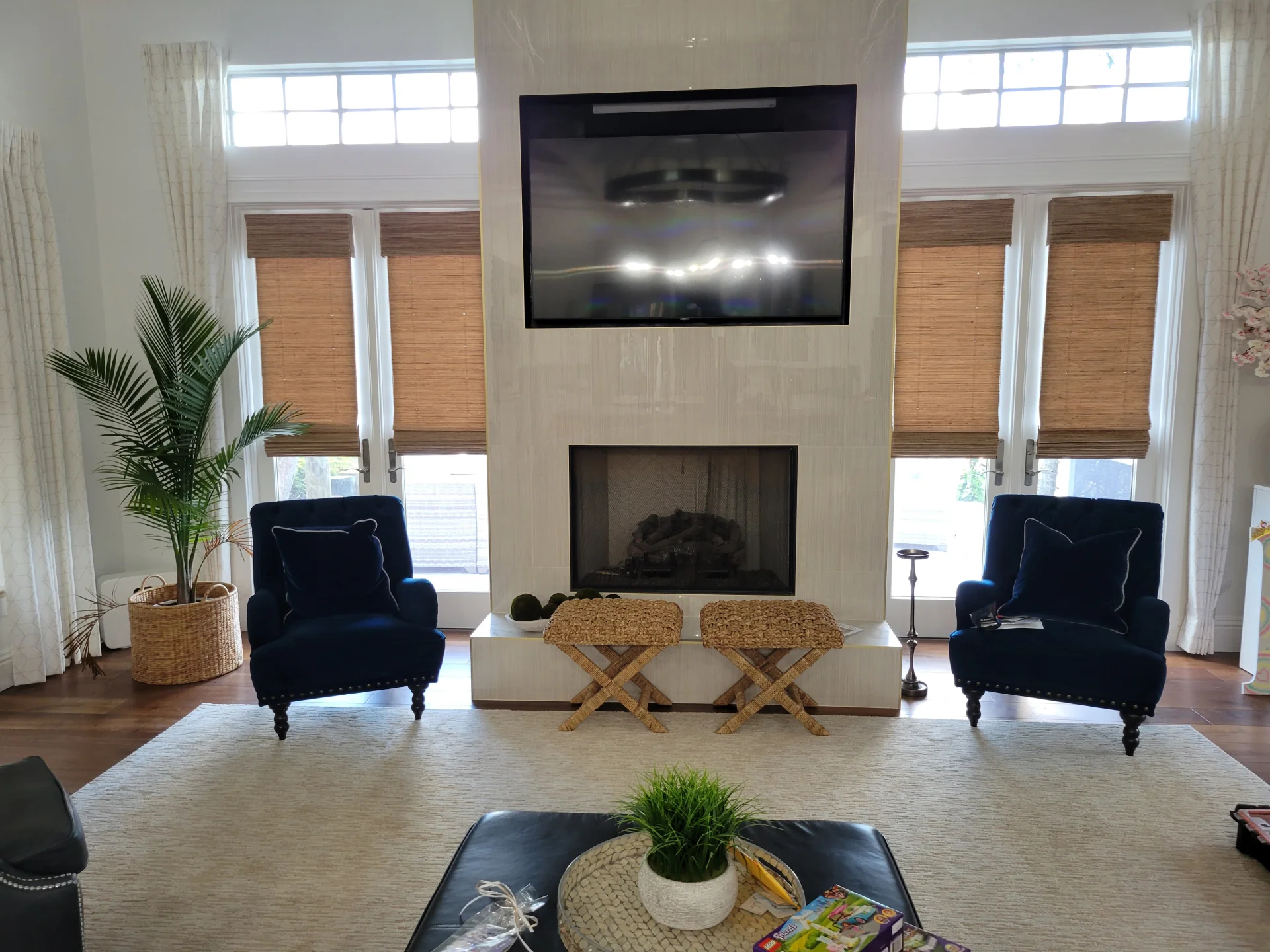 Elegant living room with custom woven wood shades flanking a modern fireplace — Seaglass Window Fashions installation